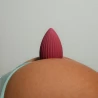 Clin d'œil coquin et espiègle avec le stimulateur clitoridien MUNA couleur rose velvet, posé délicatement sur les fesses.