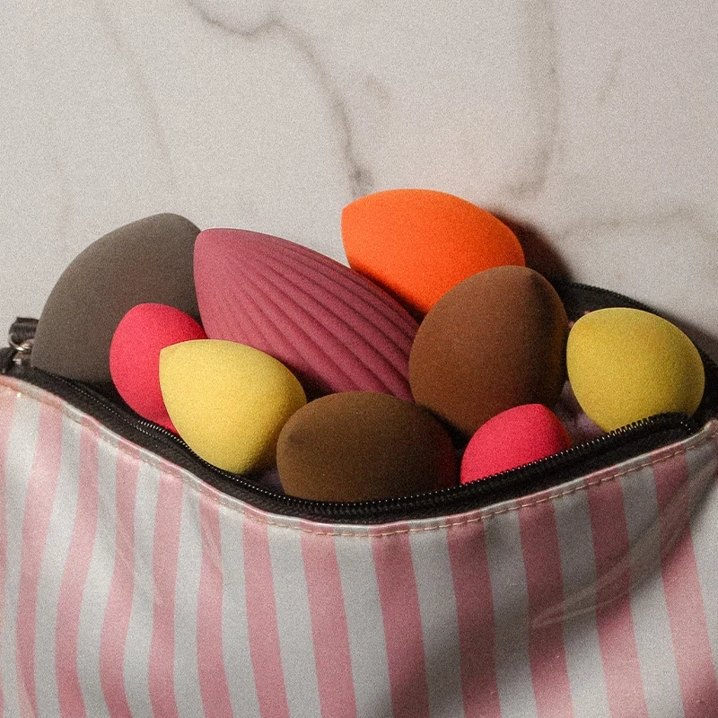 Stimulateur clitoridien Muna de Maloo ultra féminin cache dans une trousse ouverte au milieu de beauty blender colorés