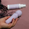 Photo d'une main de femme tenant le vibromasseur wand VARA avec la lotion nettoyante sextoys a ses cotés.